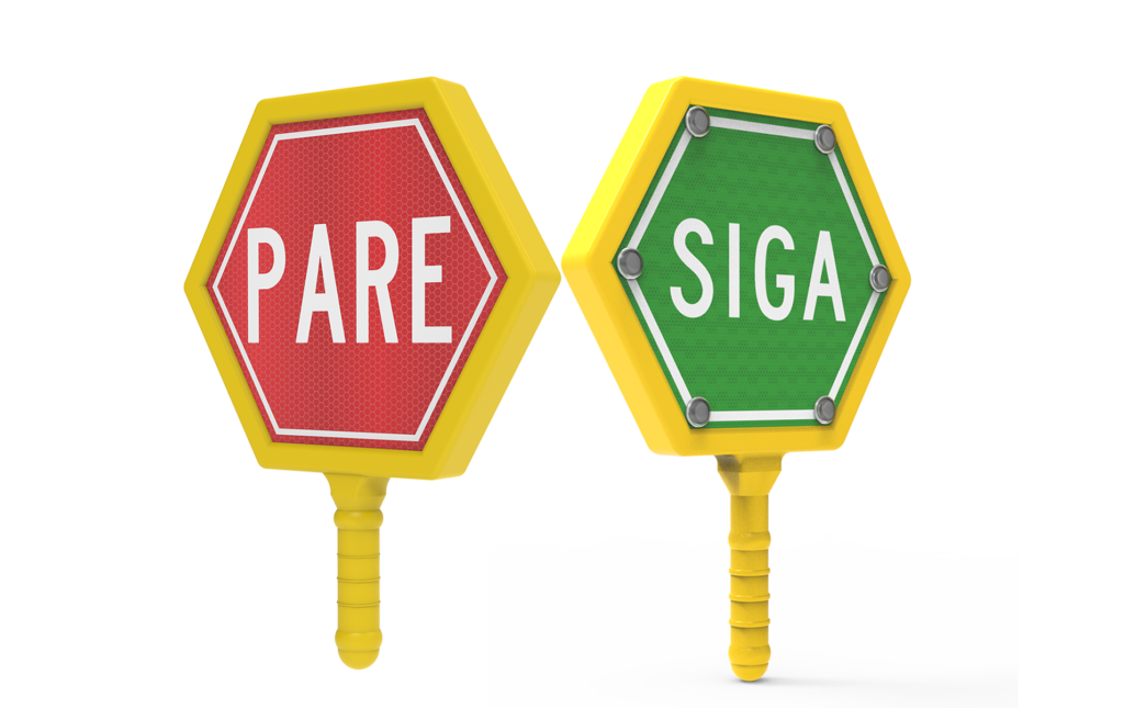 Paletas viales reversibles con marco amarillo y diseño hexagonal, una con la palabra “PARE” en rojo y otra con “SIGA” en verde. Dispositivos manuales utilizados para controlar el flujo vehicular y peatonal en zonas de obra, desvíos o eventos viales.