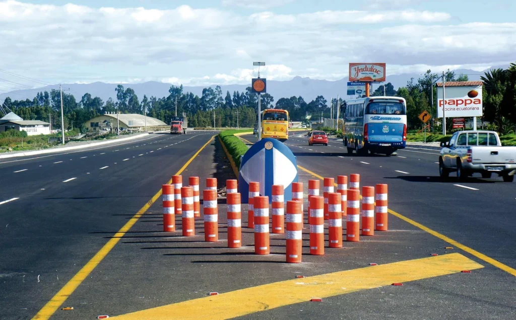 Conjunto de barriles amarillos dispuestos en forma triangular como amortiguadores de impacto no redireccionables en carretera de alta velocidad.