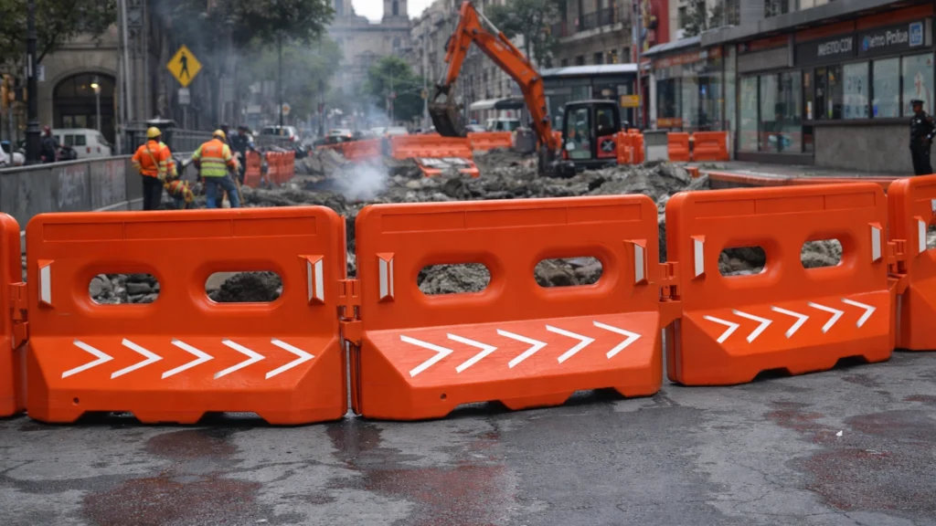 Barrera de seguridad Bulldog s81 alineada en serie para proteger el perímetro de una obra de excavación y reparación vial urbana.