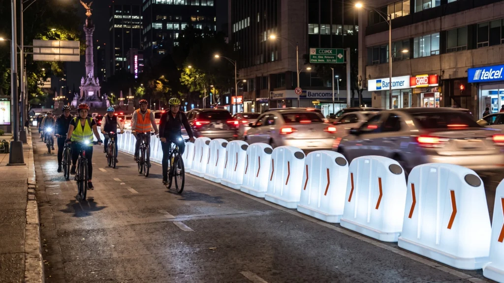 Barrera vial led en ciclovía nocturna separando carril vehicular y ciclistas en ciudad